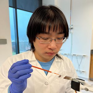 Ph.D. student Zizheng Wang places a dyed water droplet onto a ribbon array and slowly rotates the substrate to observe when the droplet begins to move (UConn Photo).
